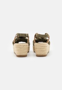 Olive green espadrille sandals with a woven jute platform, elastic ankle straps, and a soft cushioned interior.