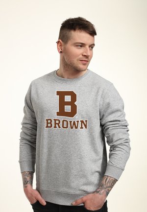 Grauer Pullover mit langen Ärmeln, der einen großen braunen Buchstaben "B" und das Wort "BROWN" darunter zeigt, prominent auf der Vorderseite.