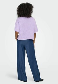 Violeta adīta džemperis ar īsām piedurknēm, saskaņots ar platajiem džinsu biksēm vidēji zilā tonī, kas piedāvā brīvu piegriezumu un teksturētu audumu.