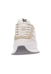 Zapatillas beige y blancas con parte superior de ante y malla, cordones planos, suela texturizada gris, logo de estrella en la lengüeta y acentos triangulares en el talón.