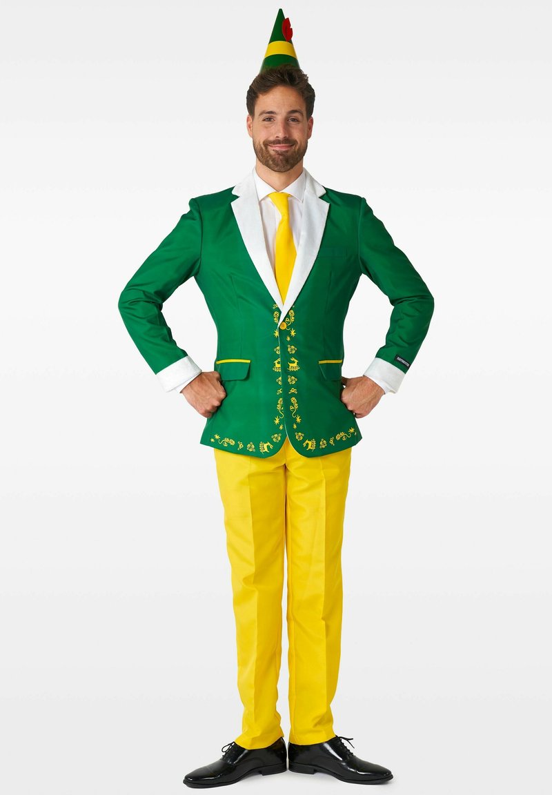 Giacca verde con rever bianchi, pantaloni gialli e cravatta gialla. La giacca presenta dettagli decorativi e un cappello festivo verde con rosso.