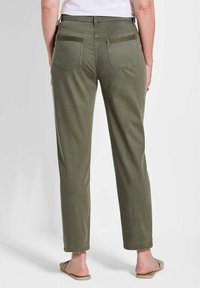 Olivegrüne Hosen aus weichem Stoff mit schmalem Schnitt. Verfügt über zwei Gesäßtaschen mit Stickdetails und einer mittelhohen Taille.