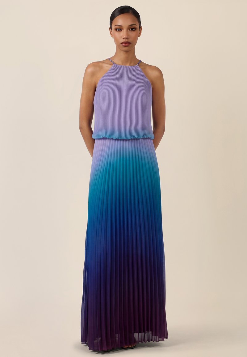 Femme portant une robe maxi plissée sans manches avec un col halter, présentant un dégradé de lavande en haut à un bleu profond et violet en bas.