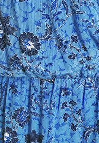 Sininen kangas tummansinisellä ja valkoisella kukkakuviolla. sisältää kerättyä tekstuuria ja pehmeää laskeutuvuutta.