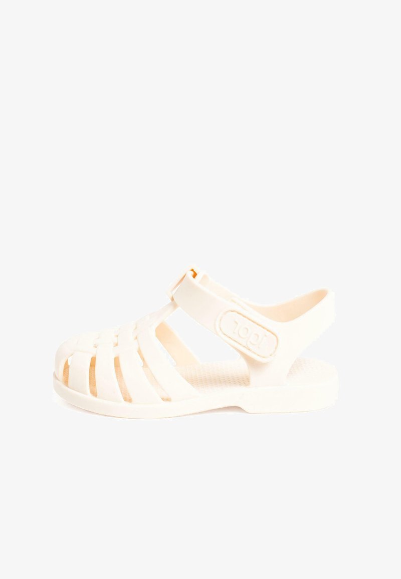 Valge plastist sandaal, millel on rihmadega disain, reguleeritav pahkluu rihm, tekstureeritud tallal ja kerge, avatud toe konstruktsioon.