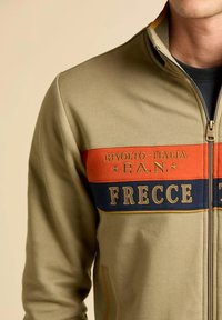 Giacca zip-up verde oliva con blocchi di colore arancione e blu navy, testo ricamato "RIVOLTO-ITALIA P.A.N. FRECCE," tessuto testurizzato.