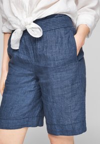 Pantalones cortos de lino azul marino con cinturilla elástica, bolsillos laterales y un acabado de tela texturizada. El dobladillo presenta un sutil detalle de costura.
