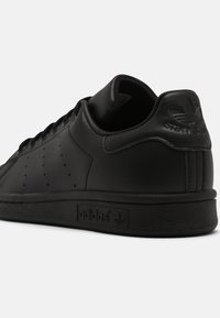 Schwarze Ledersneaker mit perforierten Seiten, flachem Schnürdesign, gepolstertem Kragen und strukturiertem schwarzen Gummisohle. Mit eingeprägtem Branding.