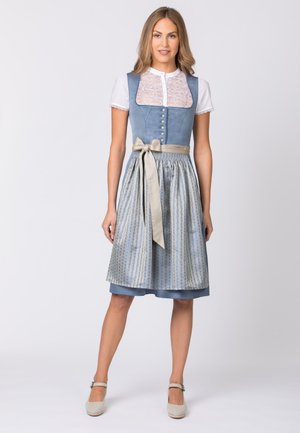 Traditionelles Kleid mit einem blauen karierten Oberteil, einer weißen Spitzenbluse darunter und einem gemusterten blau-silbernen Rock mit einer beigen Ripsbandbindung.