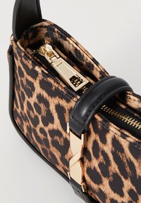 Svart och brunt leopardmönstrat handtag med guldfärgad dragkedja, svarta läderdetaljer och detaljerad hårdvara på en strukturerad design.