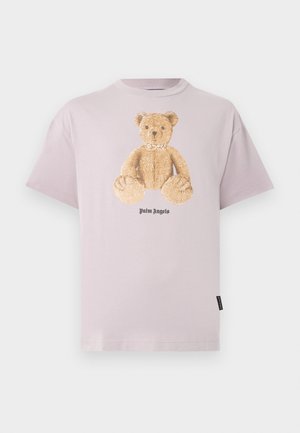 Lyserød t-shirt med korte ærmer, med en stor teddybjørne-grafik og teksten "Palm Angels" under bjørnen på frontens midte.