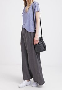 Gestreiftes kurzärmliges T-Shirt in Blau und Weiß, kombiniert mit einem grauen Maxirock. Weiße Sneakers und eine kleine schwarze Umhängetasche runden das Outfit ab.