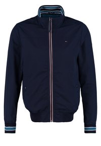 Veste zippée bleu marine avec col et poignets côtelés rayés, deux poches latérales et petit logo sur la poitrine.