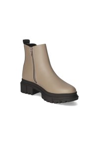 Bottine beige avec une tige en faux cuir lisse, fermeture éclair sur le côté et semelle en caoutchouc noir texturé au design épais.
