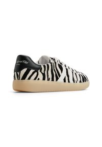 Sneakers with black and white zebra-patterned fur, featuring a smooth black leather heel and a beige rubber sole.