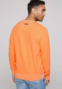 Heldoranje sweatshirt met ronde halslijn, voorzien van ribgebreide boorden en onderrand, met een gestructureerde stof en een klein label op de bovenrug.