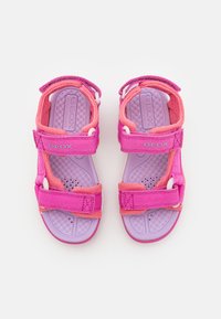 Růžové a levandulové sandály s prodyšným svrškem, nastavitelnými popruhy a texturovanými podrážkami. Obsahují bílé detaily a logo značky na boku.