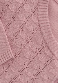 Ljust rosa stickad tröja med ett texturerat skalformat mönster och ribbade ärmslut. Tyget verkar mjukt och fint vävt.