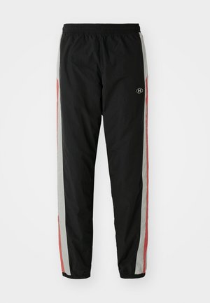 Pantalons de sport noirs avec taille élastique, présentant des rayures latérales en gris et rouge, en matériau léger, et un logo sur la cuisse gauche.