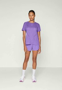 Uniform sportiv violet, format dintr-o cămașă cu mânecă scurtă și pantaloni scurți, realizat dintr-un material ușor, cu detalii subtile în pattern și accente albe.
