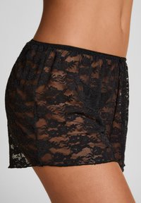 Τα μαύρα σορτς από δαντέλα διαθέτουν floral σχέδιο, διάφανα υφή και ελαστική μέση με κυματιστό τελείωμα. Το μήκος φτάνει έως το πάνω μέρος του μηρού.