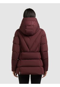 Burgundia puffer-jakk, millel on kapuuts, tikitud disain, elastsed varrukad ja silmatorkav logo seljal. Sile tekstuur ja sobiv kuju.