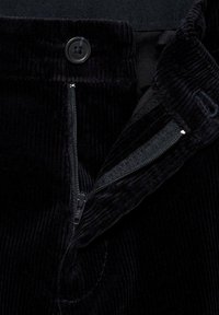 Crne kord pants hlače s prednjim gumbom i zatvaračem, s vidljivim rebrima i glatkom unutarnjom podstavom.