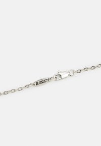 Pulseira de corrente prateada com designs interligados e fecho de clasp, com uma etiqueta gravada a ler "CLASSICS77". Textura suave.