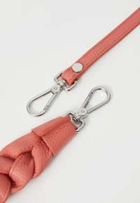 Laisse en cuir pour chien de couleur rose corail. Design tressé avec une texture lisse, dotée de quincaillerie en métal argenté et d'un mousqueton à clip.