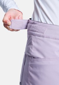 Helle lila Hosen mit verstellbarem Klettverschluss am Bund, glatter Textur und seitlichen Taschen. Der Stoff wirkt strapazierfähig und leicht.