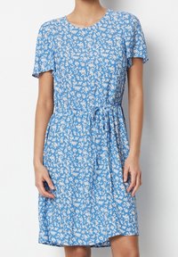 Blåblommig klänning med korta ärmar, rund halsringning och knytning vid midjan. Har en lätt, mjuk textur och små vita mönster.