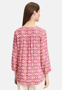 Langärmlige Bluse aus leichtem Stoff mit einem pink-weißen Wirbelmuster, mit gerafftem Rücken und rundem Halsauschnitt.