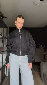 Μαύρο bomber μπουφάν με φερμουάρ μπροστά, ελαστική μέση και καStructured μανίκια. Φοριέται με φωτεινές ριγέ φαρδιές παντελόνες.