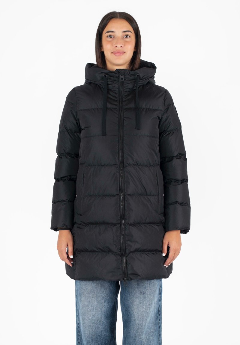 Giubbotto imbottito nero con cappuccio, caratterizzato da una chiusura a zip frontale, tasche sui lati e un motivo rettangolare cucito. Indossato sopra jeans blu a vestibilità ampia.