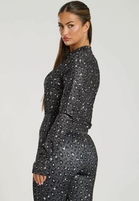 Schwarzes Sportset mit einem Leopardenmuster, das eine figurnahe Passform und lange Ärmel bietet. Weicher Stoff mit elastischem Material.