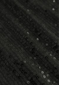 Čierny flitrový materiál s textúrovaným povrchom, obsahujúci prekrývajúce sa kruhové flitre, ktoré zachytávajú svetlo a vytvárajú trblietavý efekt.