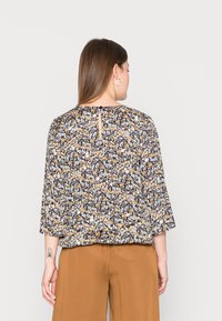 Blusa floral com fundo escuro, flores azuis e laranjas, mangas de três quartos e detalhe em fenda nas costas.