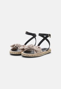 Mustat hihnalliset sandaalit, joissa on solmittu beige kangasaksentti, espadrille-tyylinen juutti-pohja ja teksturoitu musta kumipohja.