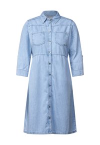 Robe chemise en denim bleu clair avec un col, devant à boutons, deux poches poitrine et des manches trois-quarts. Texture lisse, design décontracté.