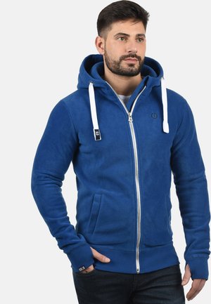 Blaue Fleece-Zip-Up-Kapuzenshirt mit einem vorderen Reißverschluss, zwei Seitentaschen, weißen Kordeln, gerippten Bündchen und gesticktem Logo-Detail.
