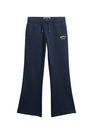 Pantalones deportivos azul marino, hechos de tela suave, con un diseño de pierna ancha y fluido, cintura elástica, cordón y una impresión blanca que dice "BROOKLYN" en el lateral.