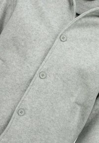 Grijs wollen overhemd met een licht gestructureerde stof, voorzien van een knoopsluiting aan de voorkant en een afgeronde kraag. Zes grijze knopen zijn zichtbaar.