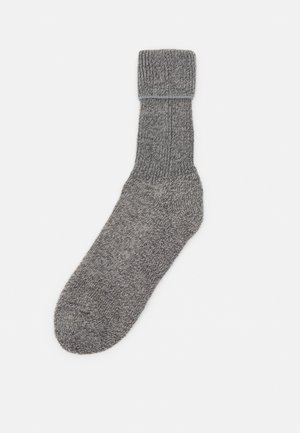 Graue gestrickte Socke mit einem gerippten Bündchen, nahtlosem Zeh und glatter Textur. Der Stoff hat ein meliertes Muster.