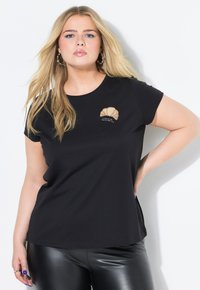 T-shirt in cotone nero con ricamo di conchiglia beige sul lato sinistro del petto. Maniche corte e scollatura rotonda.