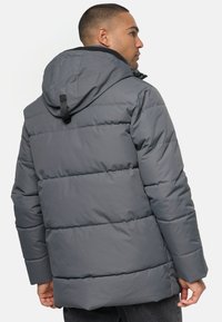 Grå pufferjakke med hætte, quiltet design og mat finish. Lynlåslommer og justerbar hætte fuldender looket.