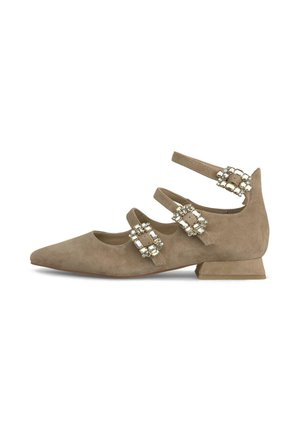 Beige suede flat with three ankle straps, embellished with decorative buckles and a low square heel. Pointed toe design.