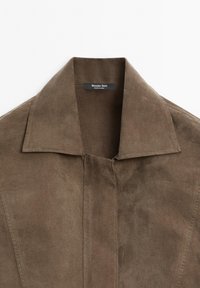 Veste en cuir suédé marron avec un col structuré, des coutures visibles et un design minimaliste. L'étiquette indique "Massimo Dutti" à l'intérieur.