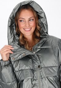 Szwajcarska szara kurtka z ociepleniem, z odpinanym kapturem, z przodu na zamek błyskawiczny i z zapięciem na guziki. Posiada pikowaną teksturę oraz elastyczne mankiety.