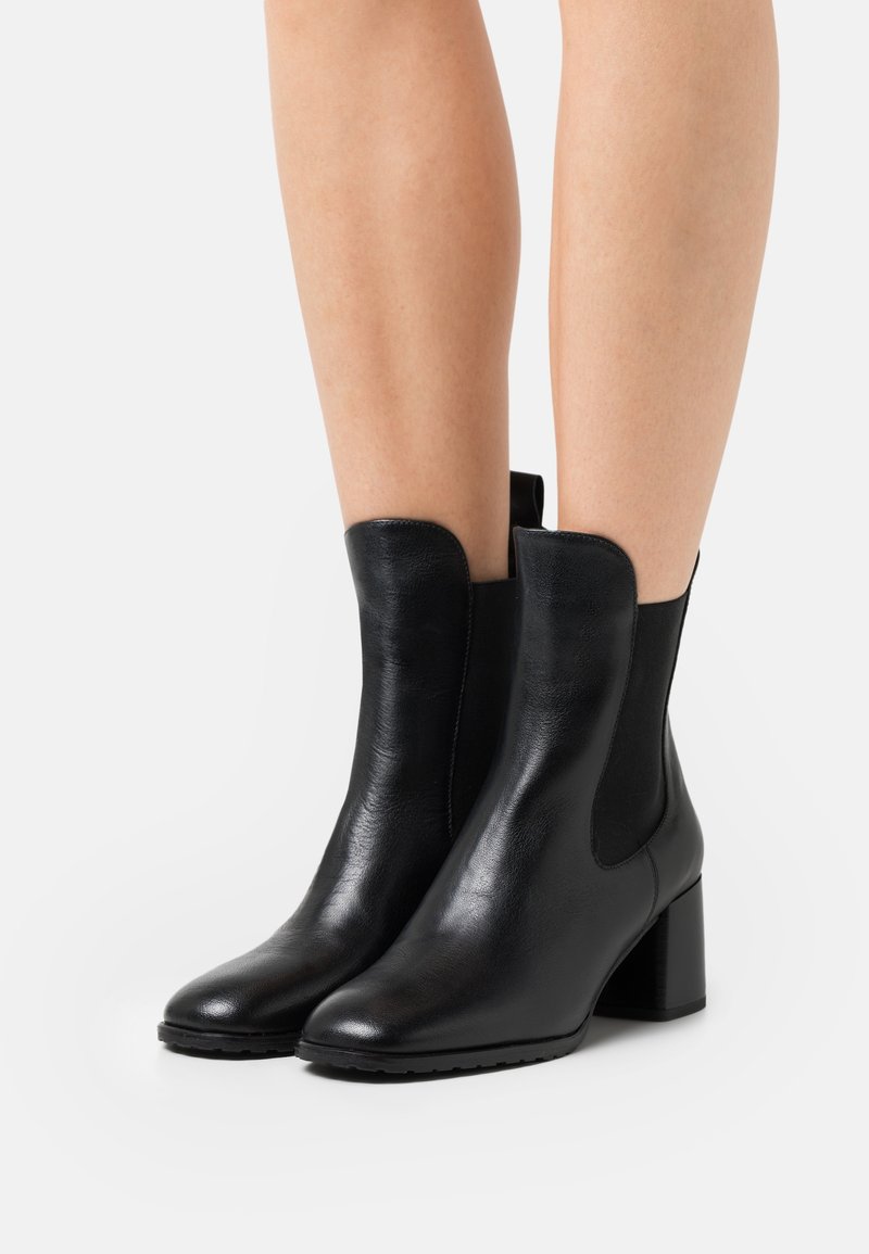 Bottines noires en cuir lisse, dotées d'un petit talon carré et de panneaux latéraux élastiques avec un design de bout rond.