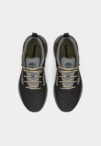 Μαύρα και γκρι αθλητικά παπούτσια Timberland με σκουρόχρωμα κορδόνια, υφή επιφάνειας, επενδυμένο γιακά και λογότυπο στη γλώσσα, με μαλακή σόλα.